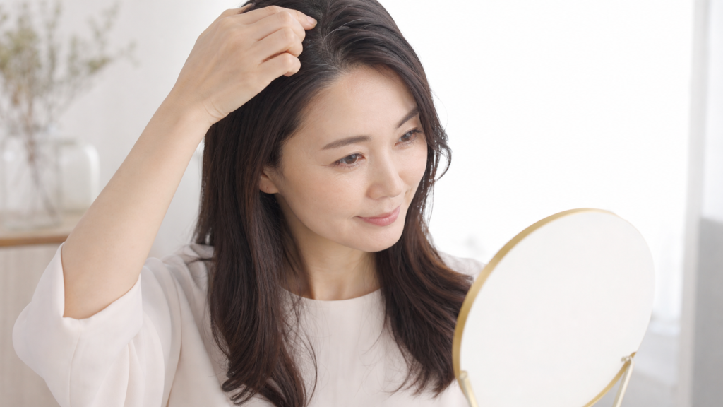 鏡で分け目の白髪を確認する女性