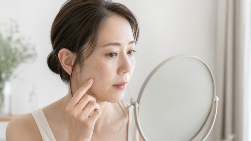鏡で頬のシミや色むらを確認する女性